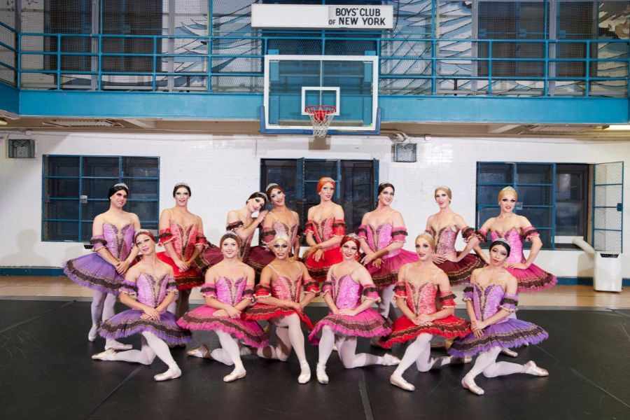 Male ballerinas pose together wearing pink and purple tutus