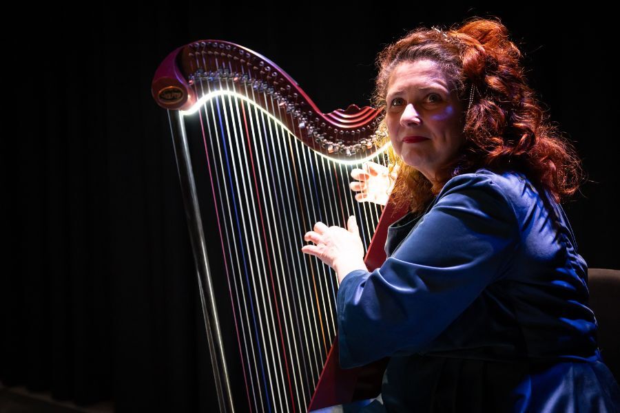 A woman with red hair plays the harp