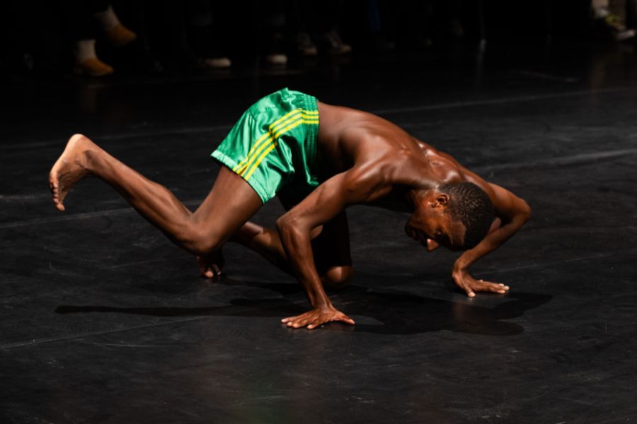 A man dancing in a breakdance position holding himself on one hand on the floor.