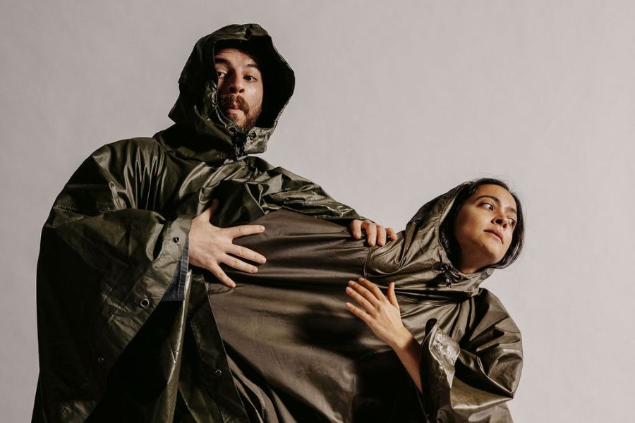 Two figures wearing storm weather gear hold on to each other