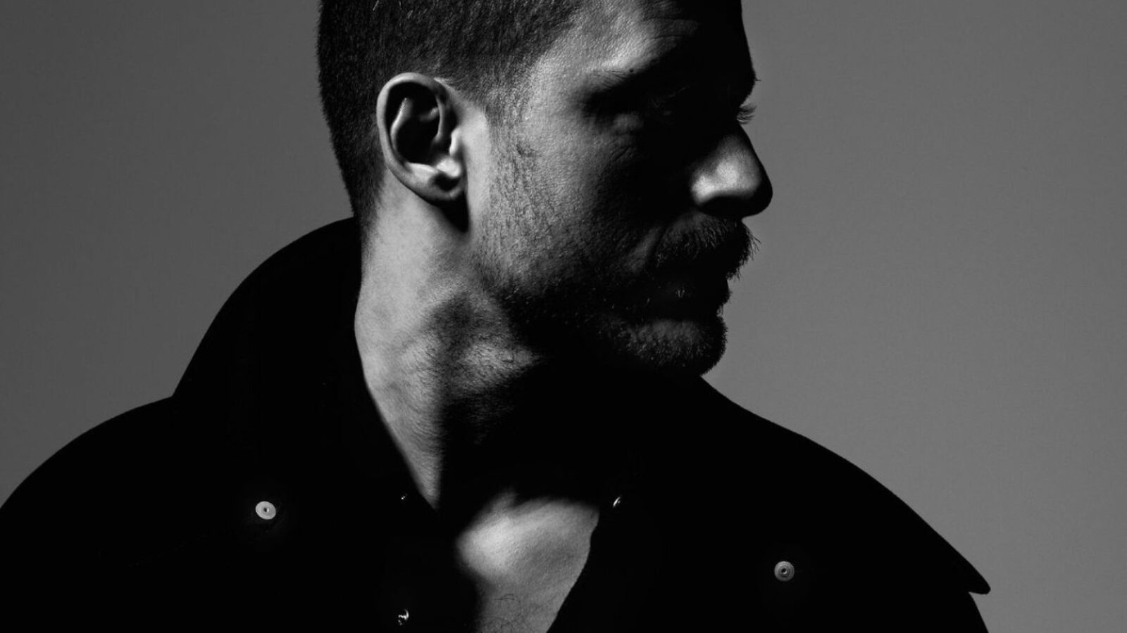 Black and white Image of a man from shoulders to head, looking off to the side.