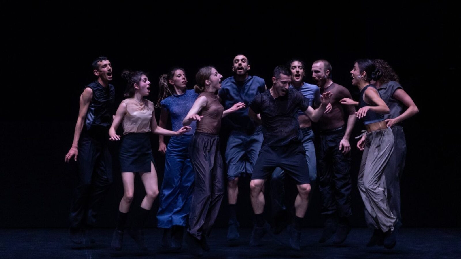 Group of dancers against a dark background.