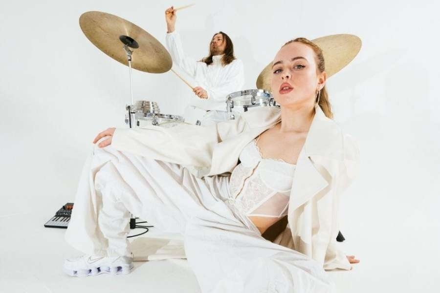 Dancer in all white in the foreground with drummer in the background