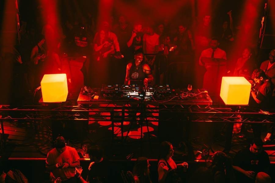 Club scene with DJ playing and the crowd dancing in the warm red glow of the lights
