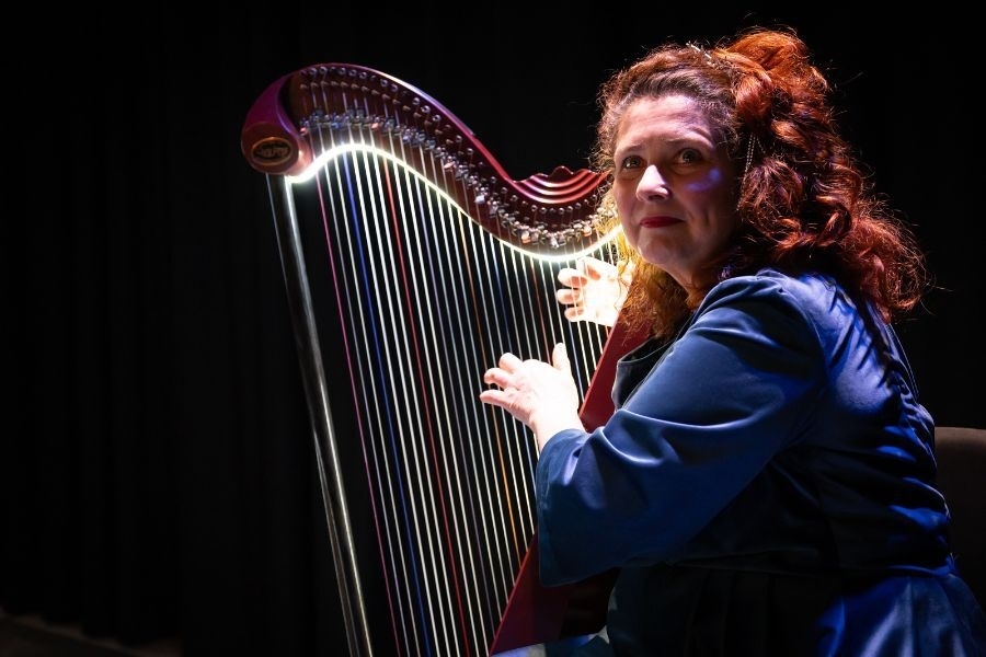 A woman with red hair plays the harp