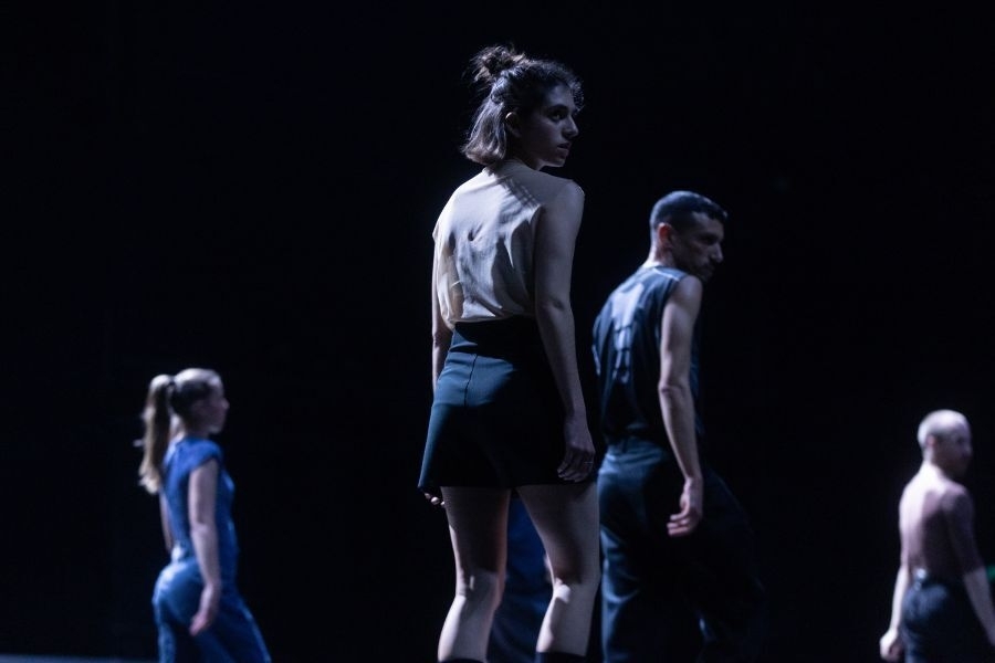 Group of dancers against a dark background.