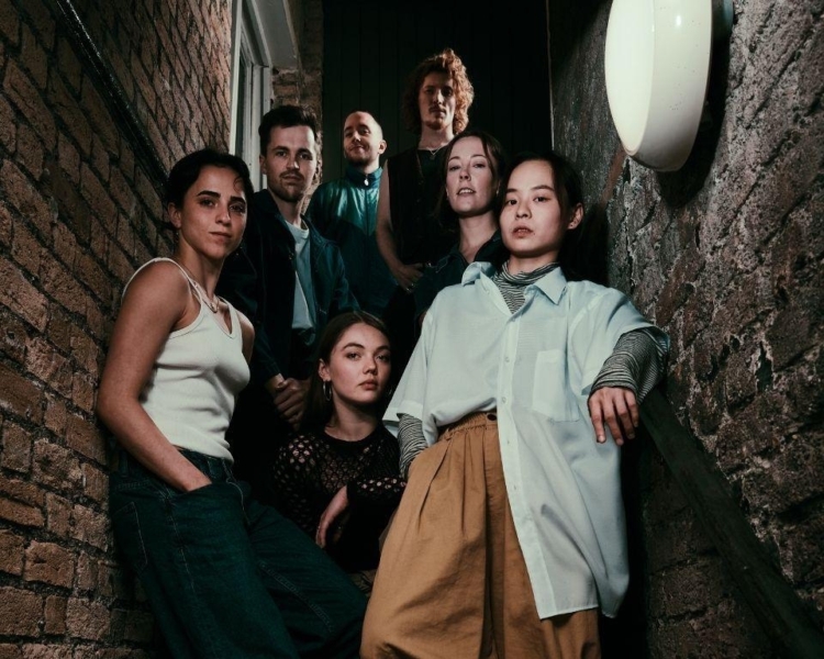 Group of dancers in a dark alley up on a stairway look down
