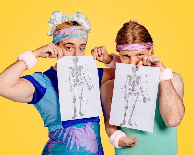 Two colourfully dressed people holding diagrams of skeletons covering part of their faces