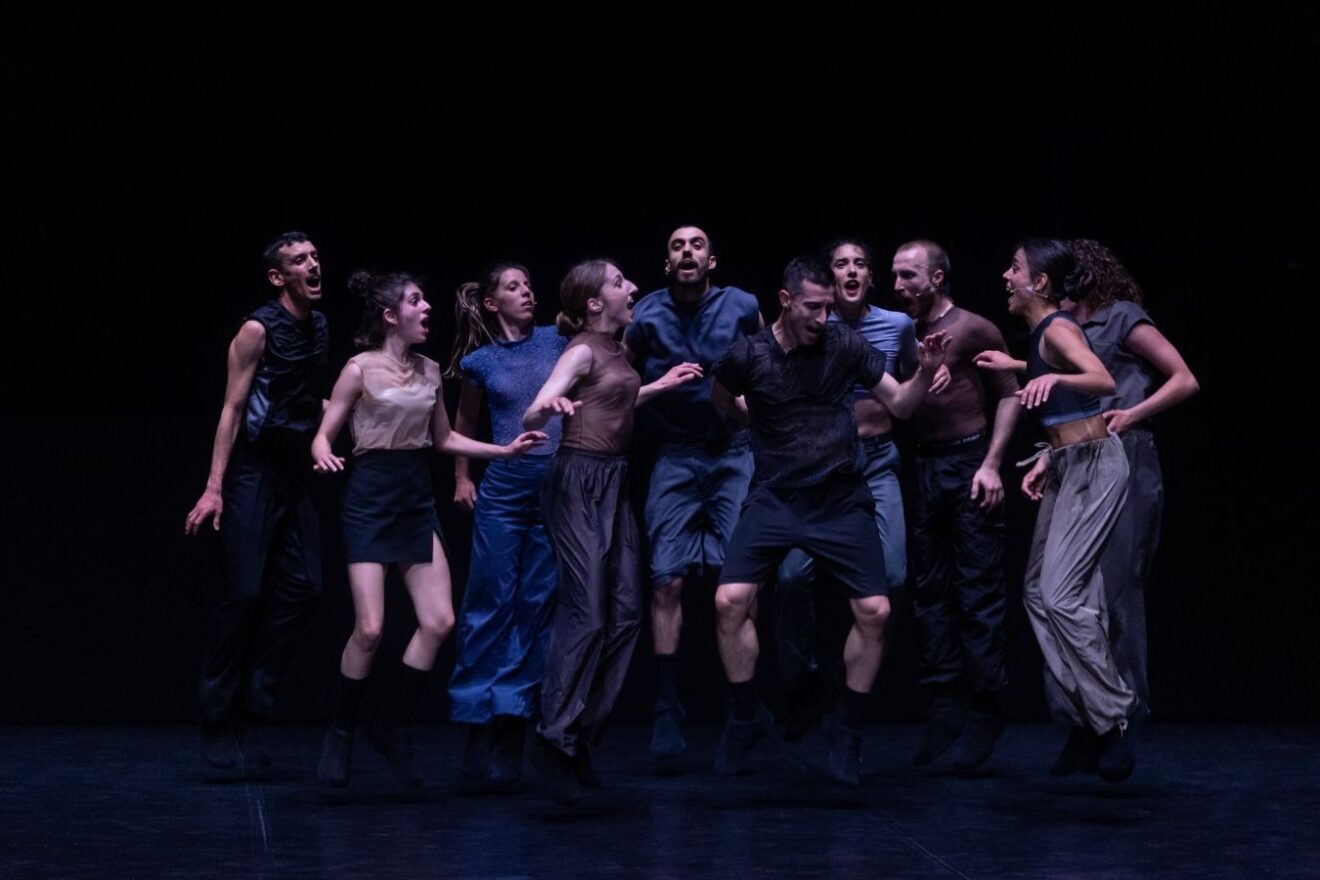 Group of dancers against a dark background.